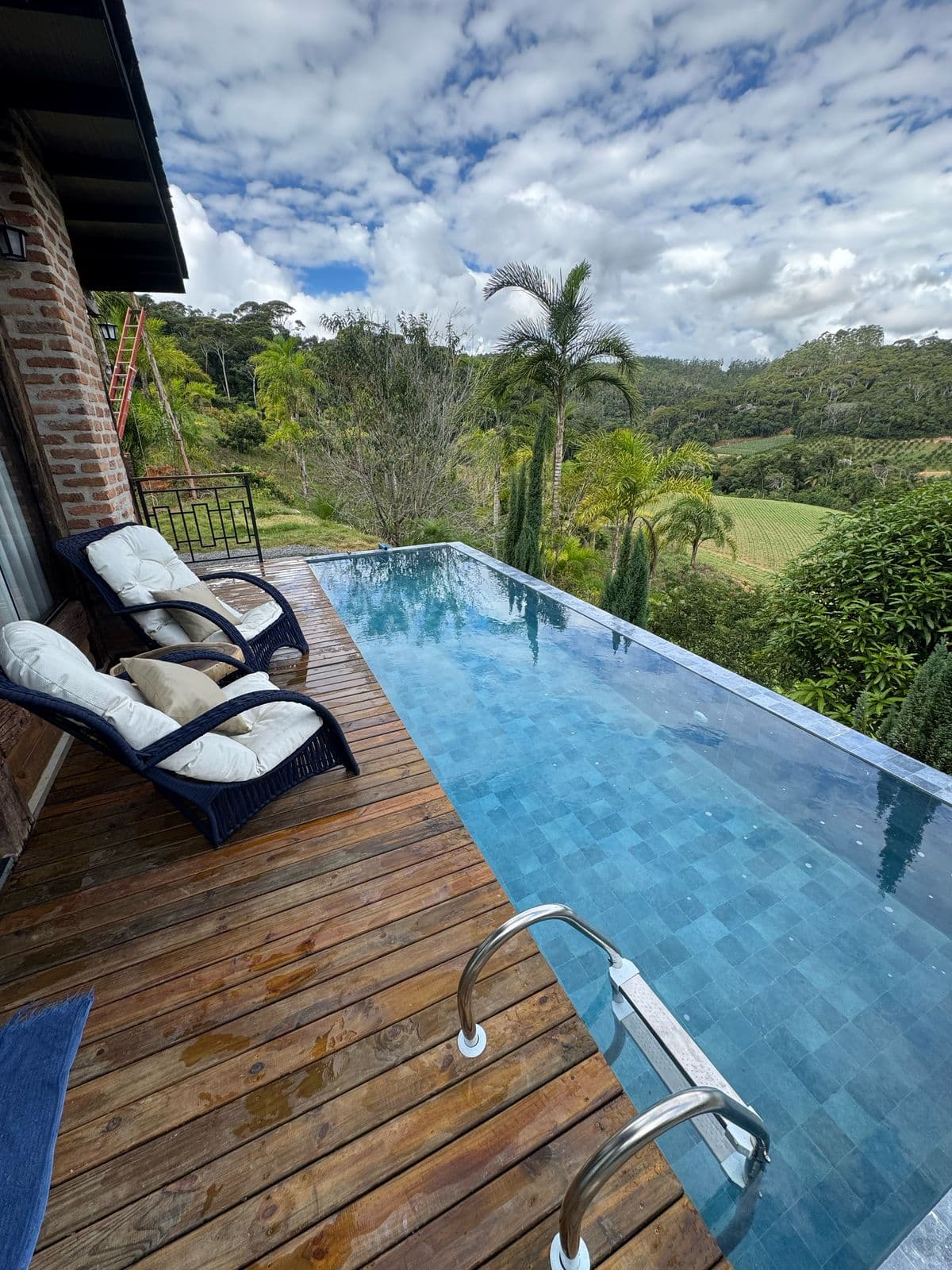 Deck e piscina de borda infinita com vista para o vale